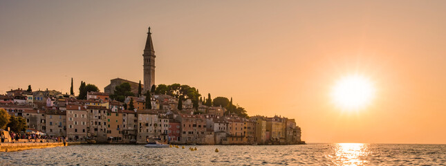 Obraz premium Golden sunset over the charming town of Rovinj, Croatia, casting reflections on tranquil waters