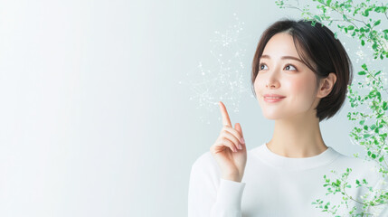 portrait of a young Japanese woman in her late 30s with short hair, wearing a white, smiling and pointing with her index finger on a plain background.
