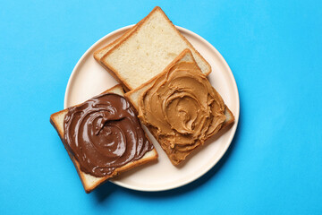 Delicious sandwiches with peanut butter and chocolate paste on light blue table, top view
