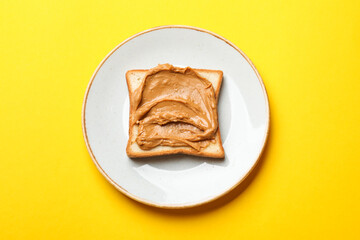 Delicious sandwich with peanut butter on yellow table, top view