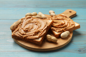 Tasty sandwiches with peanut butter and nuts on light blue wooden table, closeup