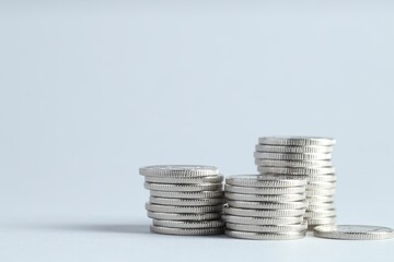 Salary concept. Stacked coins on light grey background, closeup. Space for text