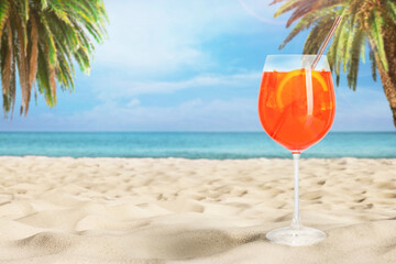 Summer beach with delicious Aperol Spritz cocktail, palm trees and golden sand, space for text