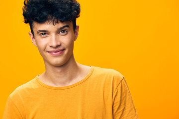 Young man smiling on a bright yellow background wearing a casual orange t shirt, embodying joy and positivity, perfect for youth oriented themes and fashion concepts