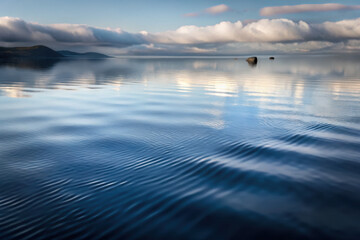 Obraz premium Gentle ripples dance across the tranquil surface of a serene lake under a bright sky, capturing the essence of calmness at dawn. Generative AI