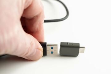 person connecting a male USB type a cable to a USB type C female connector in personal computing