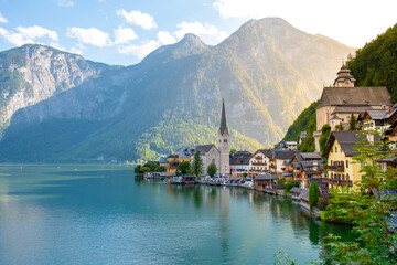 Fototapeta premium Amidst towering mountains, charming houses imbue Hallstatt with vibrant colors along the lakeside