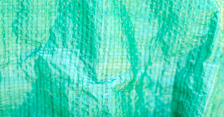 Close up of textured green plastic material with woven pattern, creating an abstract background.