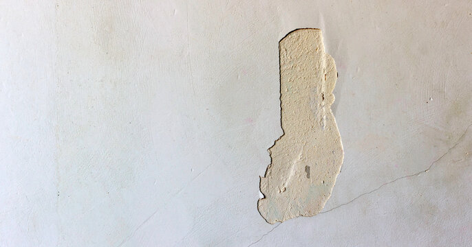 A chipped wall with peeling paint and visible texture, showing underlying plaster inminimalistic setting.