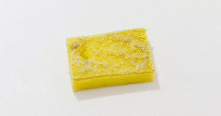 Worn out yellow cleaning sponge showing visible signs of wear and tear, ideal for concepts of hygiene and cleanliness.