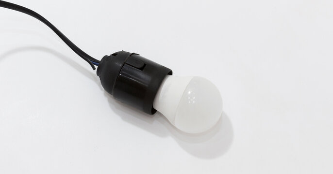 Black plastic light socket with white LED bulb attached to black cord on white background.