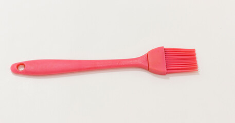 A pink silicone basting brush with hole in the handle, ideal for cooking and baking tasks.