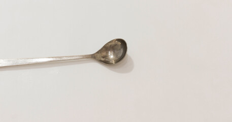 Old metal spoon on plain white background with slightly worn and rustic appearance.