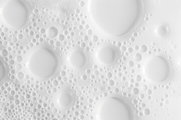 Close-up of white bubbles in different sizes on a glossy surface. Abstract texture with circular patterns.