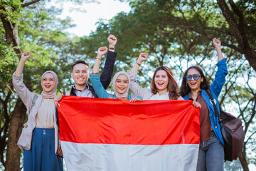 young students holding indonesian flag celebrating independence day with raised fist
