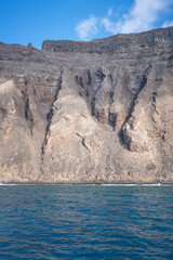 view of a volcanic cliff seen from the sea, with forms of lava falling into the sea eroded by the passing of time, vertical