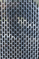 Oblong holes on a white metal sheet. Macro. Russia.