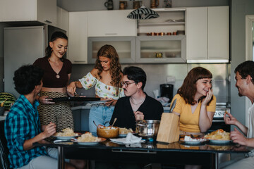 A cheerful group of friends share a meal in a modern kitchen setting. The warm atmosphere captures...