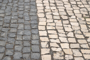 Abstract background of cobblestone pavement in two colors, gray and white, handmade Portuguese...