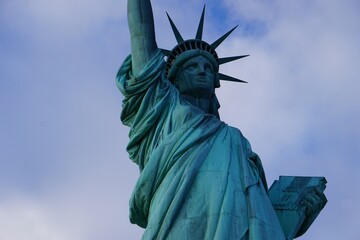 Fototapeta premium Close Up der Freiheitsstatue in New York, Symbol amerikanischer Freiheit und beliebte Tourismus Attraktion, vor wolkigem Himmel im Winter