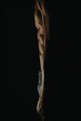 Close-up of a muscular man's torso in low light, showcasing well-defined abs and muscle tone with dramatic lighting and shadows.