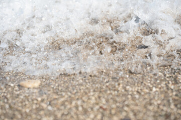 Clear water sea waves rolling on small crushed stone beach. View on ocean tides coming on brown pebble coast. Calm, relax, summertime vacations concept. Copy space for text