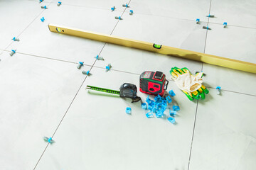 Laying floor tiles. Linear level. Green hand gloves.