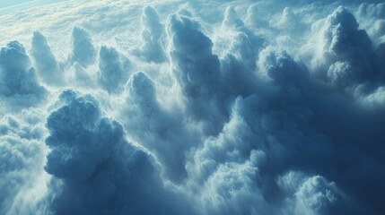 Fluffy white clouds billow and rise against a bright blue sky, creating a tranquil atmosphere. This breathtaking display of nature offers a unique aerial perspective on cloud formations