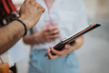 Collaborative business meeting with people discussing and using a tablet in an urban city. Focus on hands and technology.