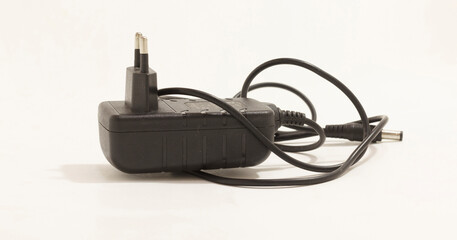 Black AC power adapter with two prong plug and attached cable, isolated on white background.