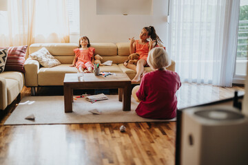 Two children and an adult enjoying a casual and playful afternoon in a cozy living room. The...
