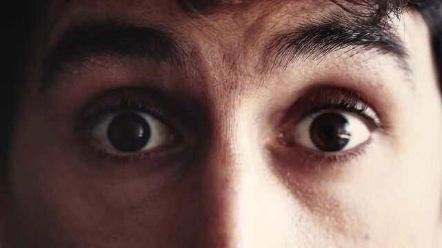 Man's eyes open wide in a close-up, showing a startled and surprised expression. His intense gaze conveys a strong reaction, highlighting a moment of unexpected shock or realization