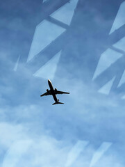A beautiful large airplane that goes for takeoff on a sunny and bright day is captured across a beautiful skyscraper with reflections in the window
