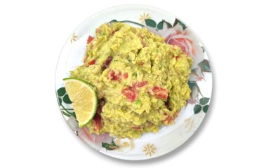 Top view of a delicious homemade guacamole plate, garnished with a slice of lime, isolated on white background.