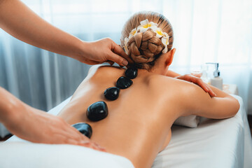 Hot stone massage at spa salon in luxury resort with day light serenity ambient, blissful woman...