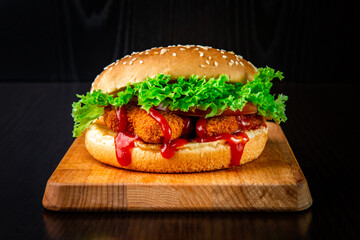 Crispy Chicken Nuggets Burger with Lettuce, Tomato and Ketchup isolated on wooden board side view...