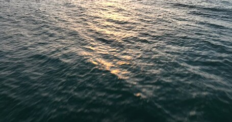 Flying over the ocean at sunset, an aerial view captures a drone flight over the sea during this beautiful time. Stunning aerial shot of the ocean at sunset. - Powered by Adobe