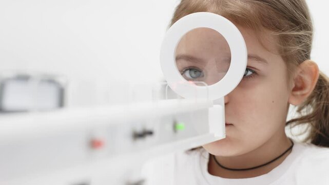 A little girl enjoys an engaging vision game on state-of-the-art ophthalmic equipment. The "Rainbow" system enhances eyesight in a comfortable and welcoming environment.