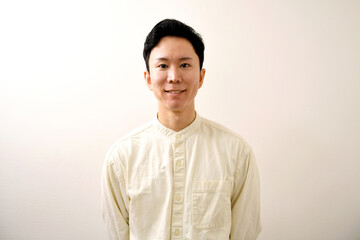 カメラ目線の笑顔の若い私服のアジア人男性