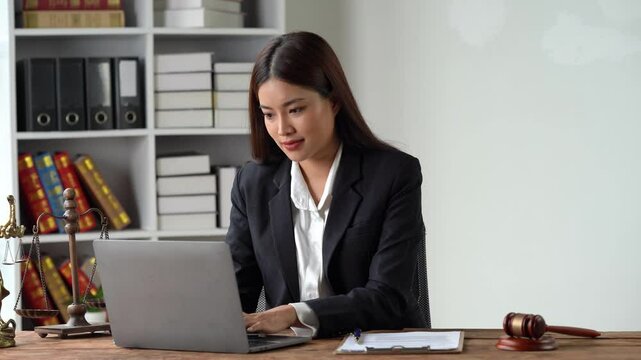 Focused Attorney: A determined female lawyer, confidently working on her laptop in a well-lit office, surrounded by legal symbols and a bookshelf filled with law books.