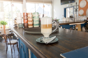 A glass of coffee sits on a wooden counter in a cafe