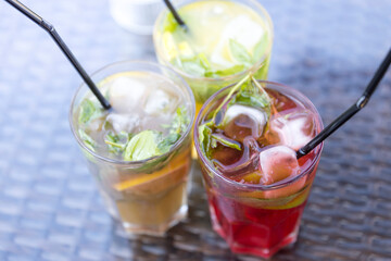Three glasses of different colored drinks with straws in them