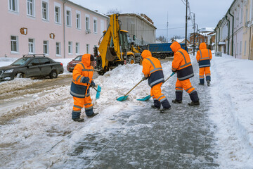 A group of workers in orange coats are shoveling snow from the street © Sergei