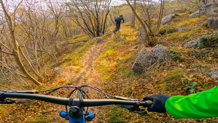 POV: Spectacular first person view of racing mountain bikes with a friend in the picturesque sunlit...