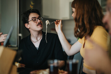 A couple sharing a lighthearted moment while having pasta for dinner at home. The playful interaction creates a warm and intimate atmosphere.