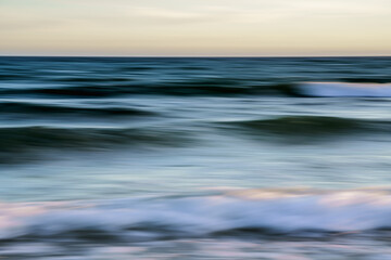 Obraz premium Soft, flowing ocean waves captured in a blur during sunset.