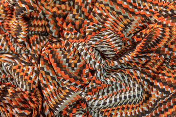 crumpled fabric background with red, orange, white, brown and black checkered pattern