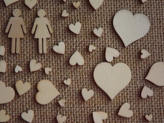 wooden hearts of different sizes and figurines of a man and a woman on jute fabric as a Valentine's day card. Declaration of love. High quality photo