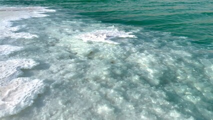 Crystallized salt meets turquoise water, highlighting rugged edges transitioning into calm liquid, showcasing natural harmony between land and sea.