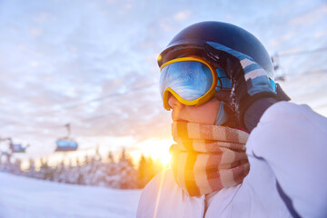Snowboarder woman on the sunset background. A mountain range reflected in the ski mask. Winter...